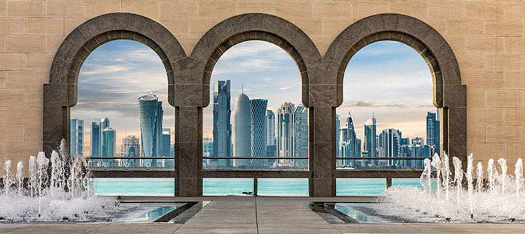 Vantage Deluxe Travel from Mumbai to Dubai Small Ship Ocean Cruise The city of Doha seen through arches, with water fountains in the foreground